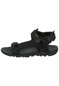 Black outdoor sandals with adjustable straps, textured rubber sole, and padded ankle support. Features plastic buckles and reinforced stitching.