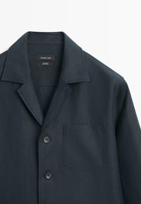 Mørk marineblå linnedjakke med slået krave, to frontknapper og brystlomme, mærket Massimo Dutti, lavet i Tyrkiet.