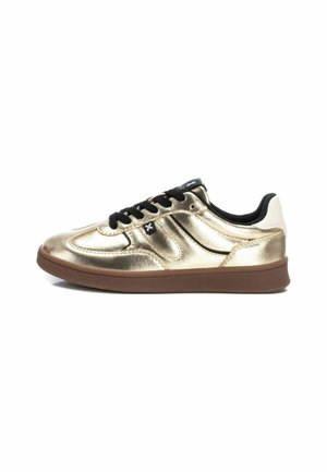 Zapatillas metálicas doradas con cordones negros, detalles en blanco en el talón y una suela de goma marrón. Presenta detalles de costura curva en la parte superior.