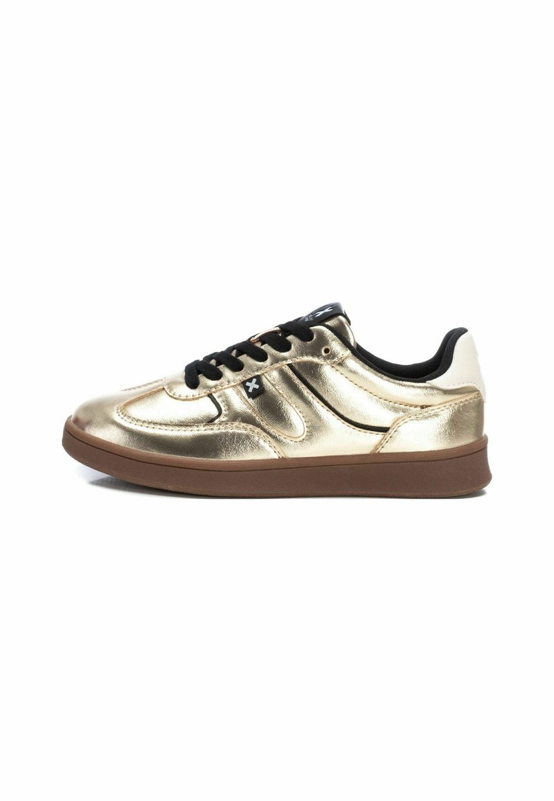 Zapatillas metálicas doradas con cordones negros, detalles en blanco en el talón y una suela de goma marrón. Presenta detalles de costura curva en la parte superior.