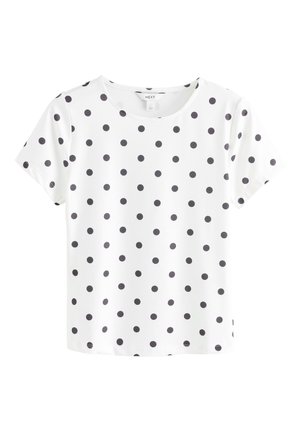 Hvid kortærmet bluse med sorte prikker, rund halsudskæring og lige kant, vist mod en ensfarvet hvid baggrund.