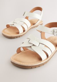 Sandales femme en cuir blanc avec brides à boucle et semelles intérieures rembourrées couleur fauve sur semelles en caoutchouc brun clair.