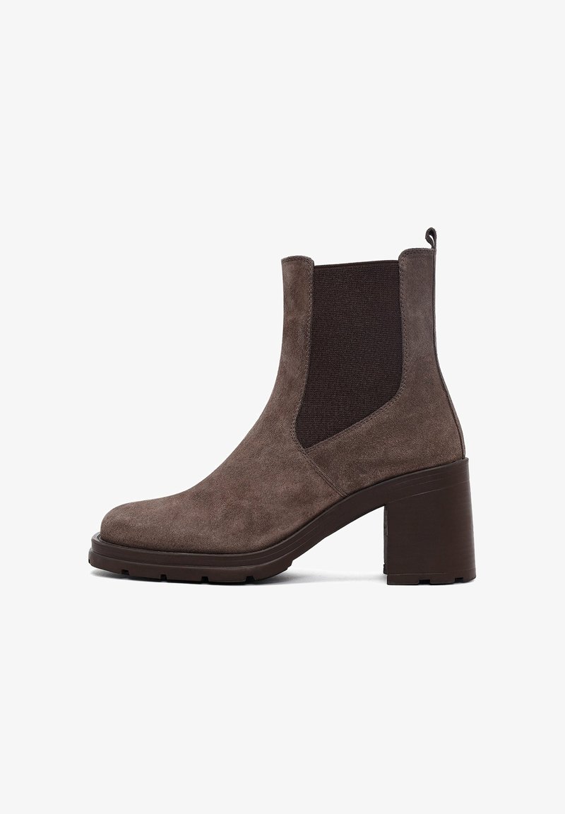 Stivale ankle in suede marrone con pannelli elastici ai lati, punta tonda e tacco chunky. Presenta una superficie texturizzata e una linguetta per facilitare l'indossamento.