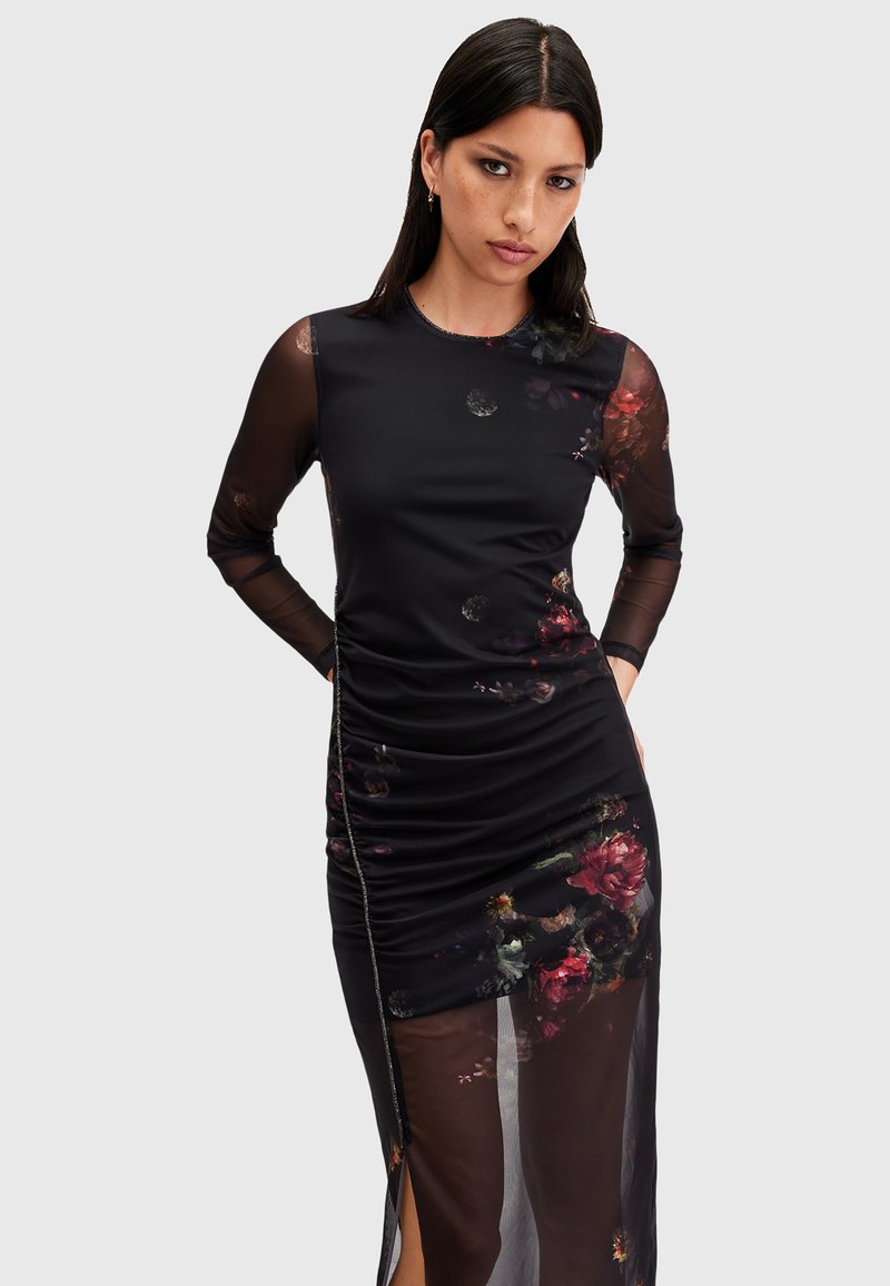 Vestido negro con mangas largas de tul, patrones florales, recogido en el lado y una alta abertura. Tejido suave con acentos texturizados y un diseño ajustado.