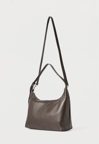 Geantă de umăr din piele maro cu o textură netedă, formă curbată și curea ajustabilă, având o închidere cu fermoar pe marginea superioară.