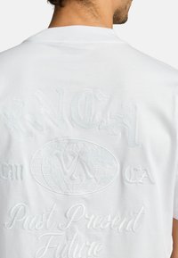 Weißes Baumwoll-T-Shirt mit erhabenem Text und einem Globusdesign auf dem Rücken, mit subtiler Textur und hellblauen Nähten.