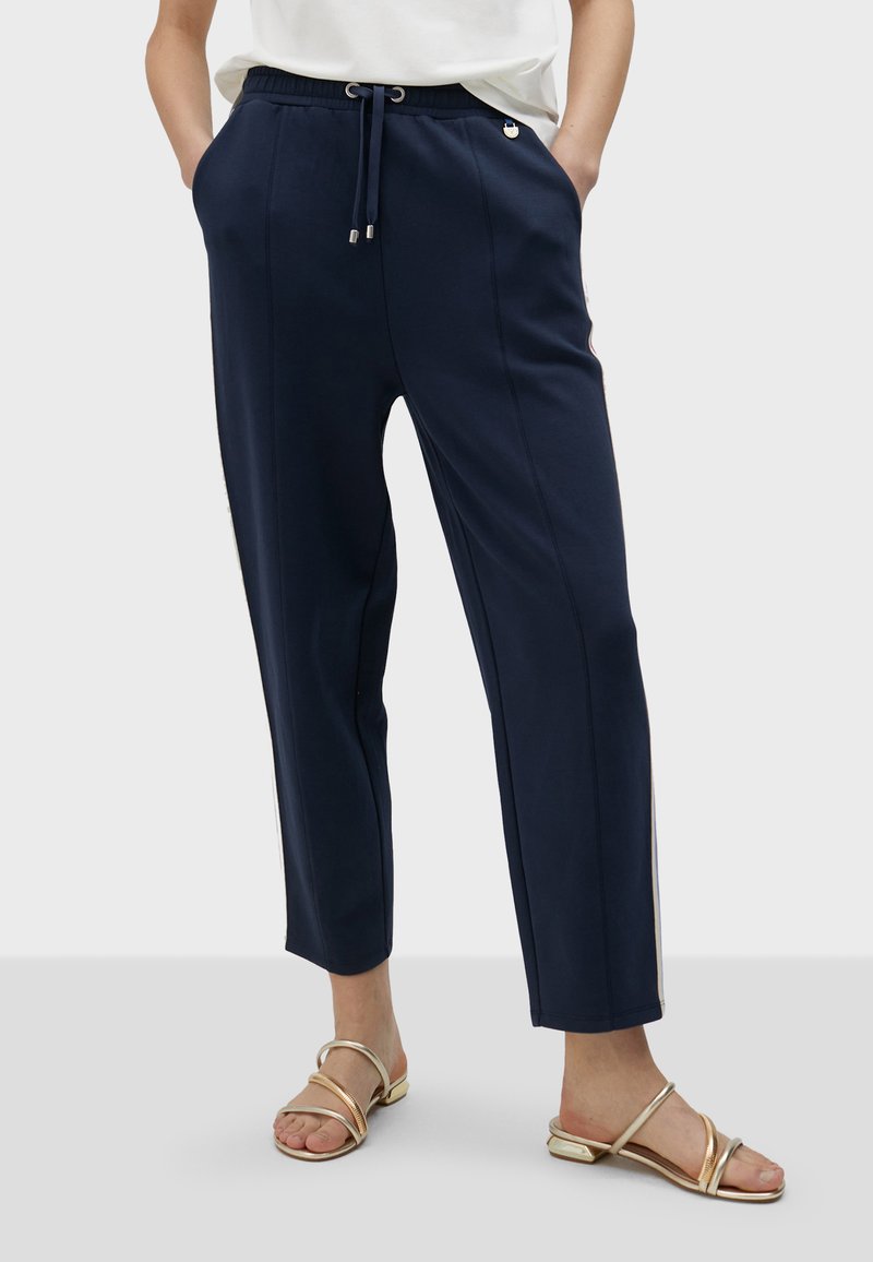 Mornarsko plavi hlače s pojasom na vezicu, s bočnim džepovima i ravnim krojem. Glatka tkanina s kontrastnim bočnim prugama.