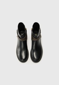 Black leather ankle boots with a smooth texture, featuring a dark patterned strap and gold hardware accents at the side zippers.