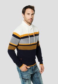 Strikket sweater med skiftevis vandrette striber i hvid, sennepsgul og marineblå med høj krave og snøre.