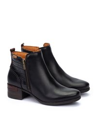 Botas de tobillo de cuero negro con un cierre lateral, con un panel embosado de cocodrilo texturizado y un tacón bajo en bloque. Detalles en marrón adornan el diseño.