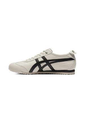 Biały niski sneaker z czarnymi paskami, białymi sznurowadłami, teksturowaną podeszwą i pętlą na pięcie, pokazany z profilu zewnętrznego.