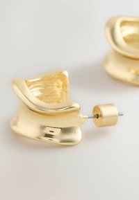 Zelta metāla auskari ar viļņotu dizainu, izceļas ar pulētu spīdumu un cilindrisku stiprinājuma stieni. Redzama teksturēta iekšpuse.