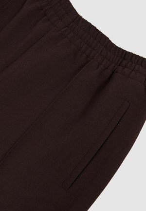 Pantaloni jogger de culoare marron închis, confecționați dintr-un material moale, cu un elastic în talie și un buzunar lateral cu un design fără cusături.