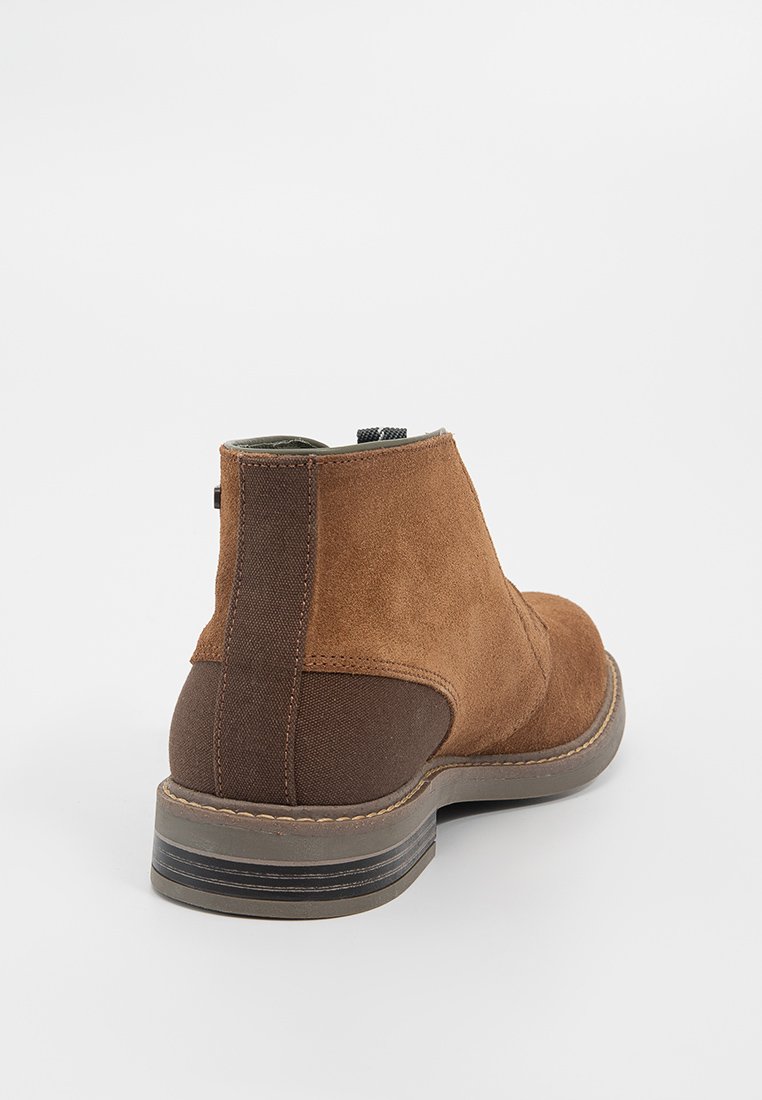 Stivale alla caviglia in suede marrone con punta arrotondata, pannello in tessuto marrone scuro a contrasto, dettagli cuciti e suola in gomma testurizzata.