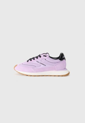 Zapatillas de ante morado con acentos negros, que presentan cordones redondos, una entresuela blanca y una suela de goma texturizada. Detalle del logo en el lado.