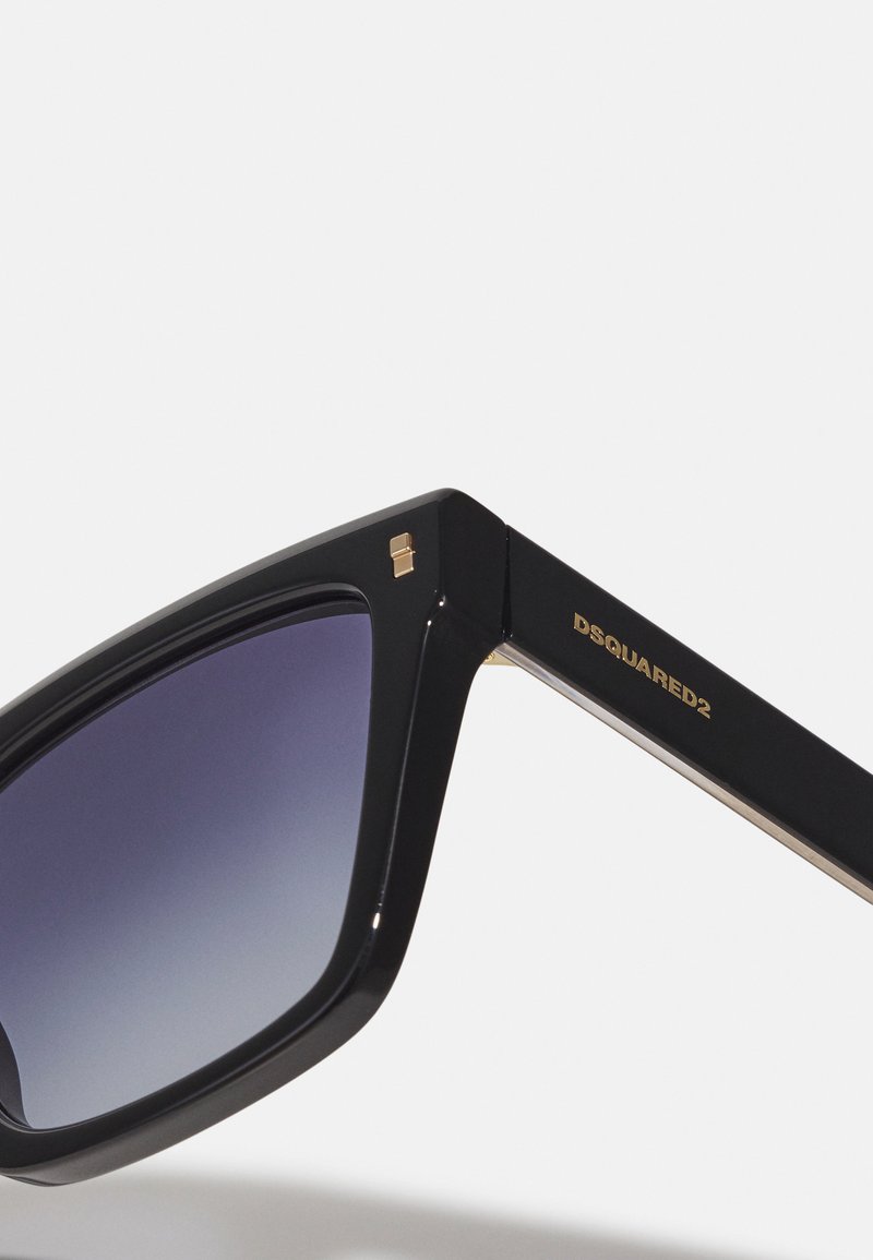 Lunettes de soleil noires rectangulaires avec des verres dégradés, une finition brillante, des accents en métal doré et un logo gravé sur la branche.