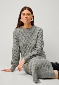 Robe en maille cablée grise avec de longues manches, col côtelé et fentes sur les côtés, confectionnée dans un tissu doux et texturé.
