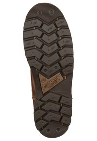 Semelle en caoutchouc noir avec un motif de semelle marqué, comprenant des rainures et un patch en forme de losange étiqueté "DOCKERS FOOTWEAR."