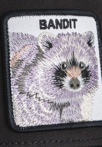 Parche bordado con un mapache en tonos de gris y púrpura, con textura de pelaje detallada, acentos en negro y el texto "BANDIDO" en la parte superior.