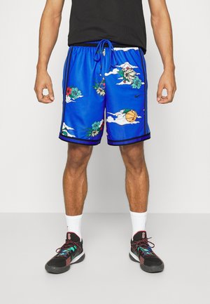 Homme portant un short de basketball bleu avec des motifs floraux et nuageux, des chaussettes blanches et des chaussures de sport noires avec des lacets colorés.
