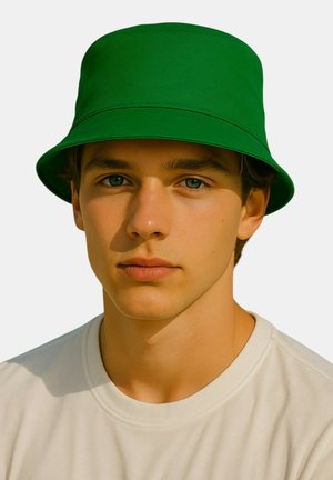 Zielony kapelusz z szerokim rondem wykonany z gładkiego materiału, z usztywnioną kopułą, noszony na białej koszulce.