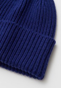 Gestrickte Mütze in tiefem Marineblau mit gerippter Struktur und umgeschlagenem Bund. Hergestellt aus weicher, dicker Wolle für Wärme.