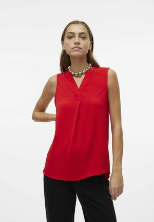 Rode mouwloze blouse met een V-hals, van textuurstof en met een losse pasvorm, gecombineerd met zwarte broek en een metalen ketting.