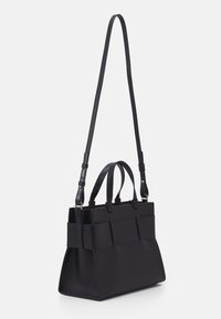 Black handbag with dual top handles and a detachable shoulder strap. Features a structured design, smooth texture, and panel accents.