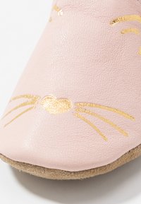 Rosa lærslipper med gullkanter og et hjerteelement. Myk tekstur med rund tå og en beige, semsket såle.