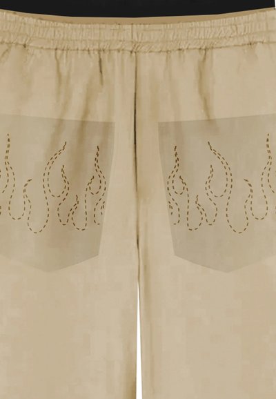 Pantaloni beige con vita elastica, dotati di due grandi tasche decorate con design cuciti a forma di fiamma in marrone. Tessuto dalla consistenza liscia.