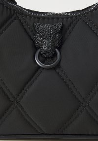 Sort quiltet nylon taske med et struktureret panterhovedlås med sorte udsmykninger og en metalring, der fremhæver de intrikate design detaljer.