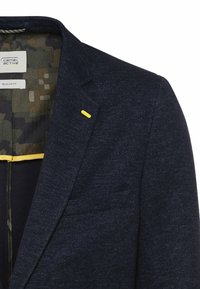 Blazer texturé bleu foncé pour homme avec revers cranté, surpiqûres jaunes et doublure intérieure à motif camouflage.