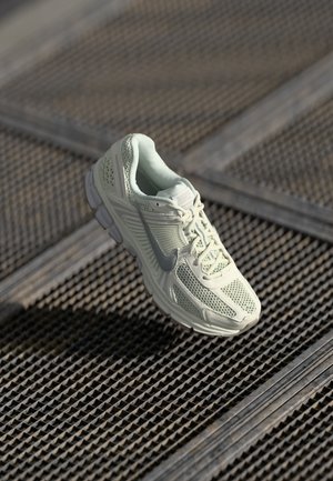 Lichtgroene sport schoen gemaakt van mesh en synthetische materialen, voorzien van een vetersluiting, een gepolsterde kraag en een rubberen buitenzool met een getextureerde grip.