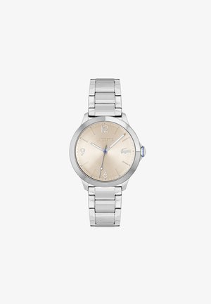 Reloj de pulsera plateado con caja redonda, esfera beige y acentos azules. Pulsera de eslabones de metal con acabado pulido. Marca Lacoste exhibida.