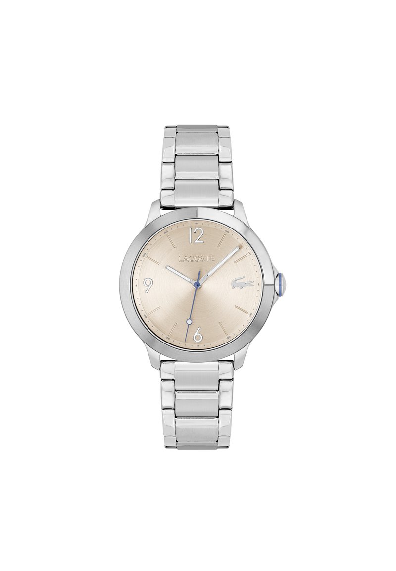 Reloj de pulsera plateado con caja redonda, esfera beige y acentos azules. Pulsera de eslabones de metal con acabado pulido. Marca Lacoste exhibida.