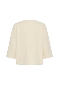 Vue de dos d'une chemise unie, couleur crème, à manches longues, coupe ample, sans motifs ni décorations visibles.