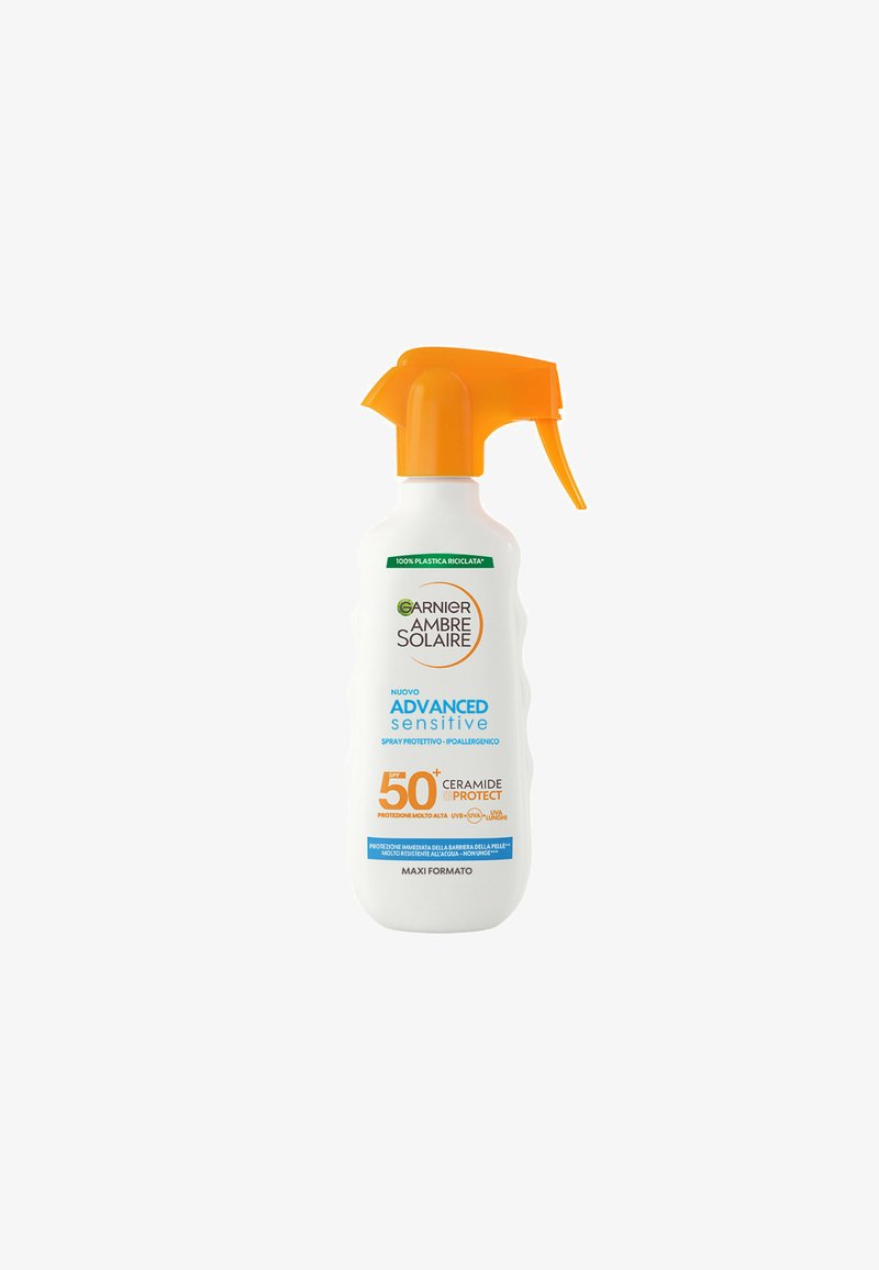 Flacone spray bianco con beccuccio arancione; etichettato con "Garnier Ambre Solaire Advanced Sensitive," con dettagli su protezione SPF 50+ e ceramidi.