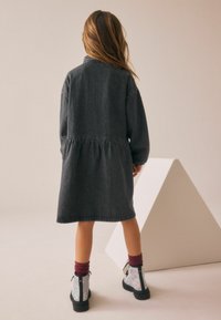 Abito di denim scuro con maniche lunghe, vita arricciata e taglio dritto. Abbinato a stivaletti glitterati e calze bordeaux.