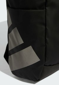 Mochila negra hecha de nylon texturizado, con un prominente patrón geométrico gris. Incluye un bolsillo lateral y costuras reforzadas.