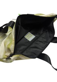 Duża torba tote z zielono-kremowym abstrakcyjnym wzorem, czarnym wnętrzem, zamykana na zamek błyskawiczny na górze oraz z wewnętrzną kieszenią na zamek do organizacji.