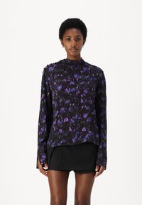 Long-sleeve blouse in black fabric with a floral pattern in purple and blue. Features a relaxed fit and high neckline with side slits.
