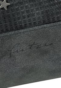 Portefeuille noir texturé avec un accent en étoile et un logo en relief. La surface est lisse avec un motif subtil et des bords cousus.