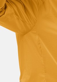 Giacca leggera gialla con tessuto testurizzato, finitura liscia e dettagli di ventilazione sui lati per la traspirabilità. Orlo con zip.