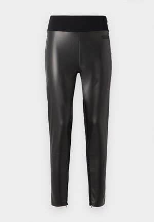 Melnas mākslīgās ādas bikses ar elegantu dizainu, kurām ir plata elastīga josta un rāvējslēdzēja apakšas, ļaujot pielāgot fit.