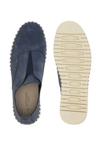 Des chaussures bateau en cuir, à enfiler, avec des côtés élastiques, une semelle en caoutchouc texturée et des coutures contrastantes de couleur crème sur le bord.