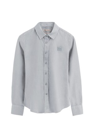 Camisa abotonada gris claro hecha de tejido suave, con un cuello clásico y mangas largas, que presenta un pequeño logo bordado en el pecho.