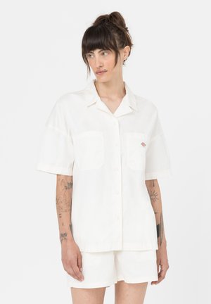 Camicia bianca a maniche corte, con bottoni sul davanti e due tasche sul petto. Tessuto morbido e leggero con un design semplice e un piccolo logo sulla tasca.