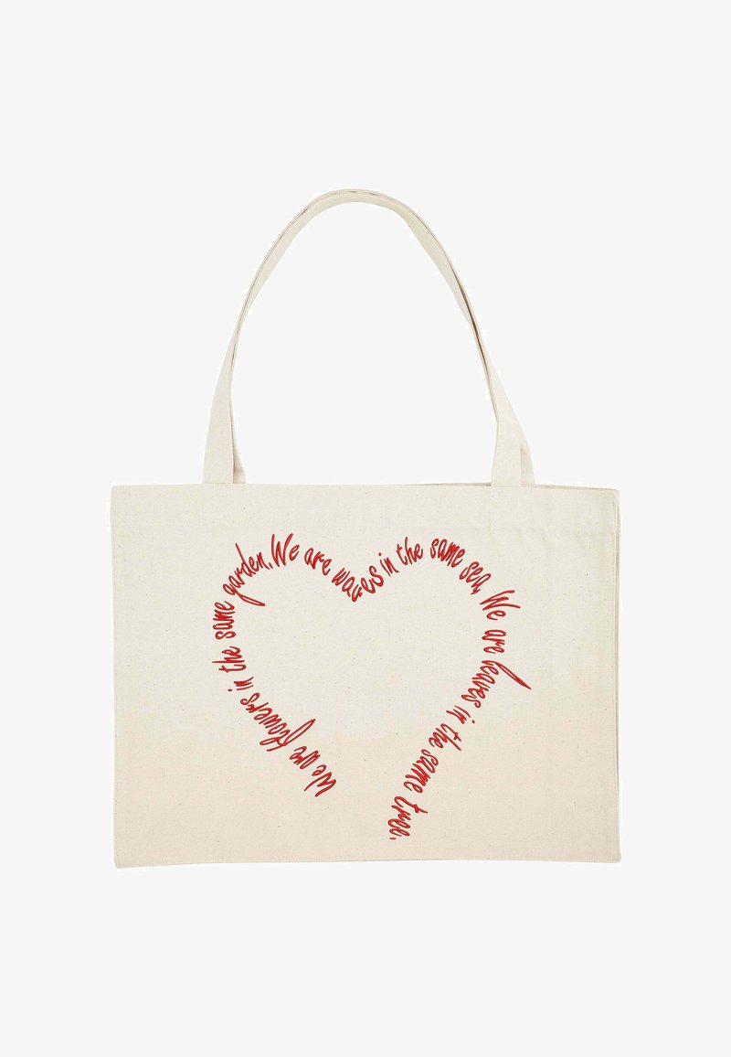 Sac en toile avec de longues poignées, couleur beige, comportant un texte rouge formant un cœur avec une citation sur l'unité et la nature.