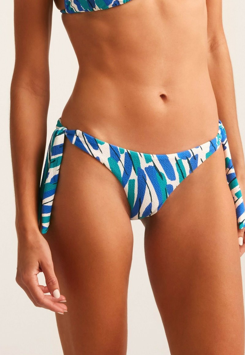 Parte inferior de bikini con una tela texturada en patrones abstractos en azul y verde. Presenta cintas laterales para un ajuste ajustable y un corte bajo.