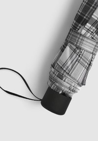 Parasol w czarno-białą kratę z okrągłą czarną rączką, wykonany z teksturowanej tkaniny i wyposażony w pasek do zapięcia zapewniający bezpieczne przechowywanie.